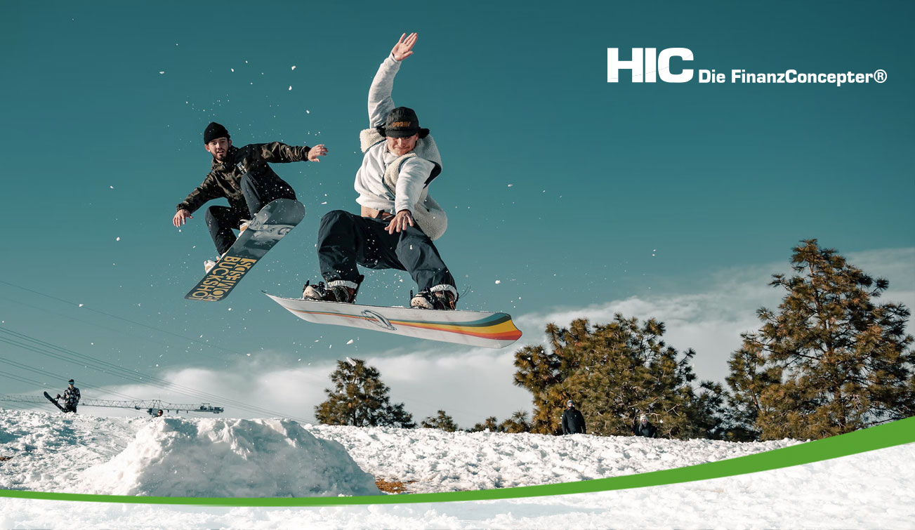 Zwei Snowboarder beim Sprung auf der Piste