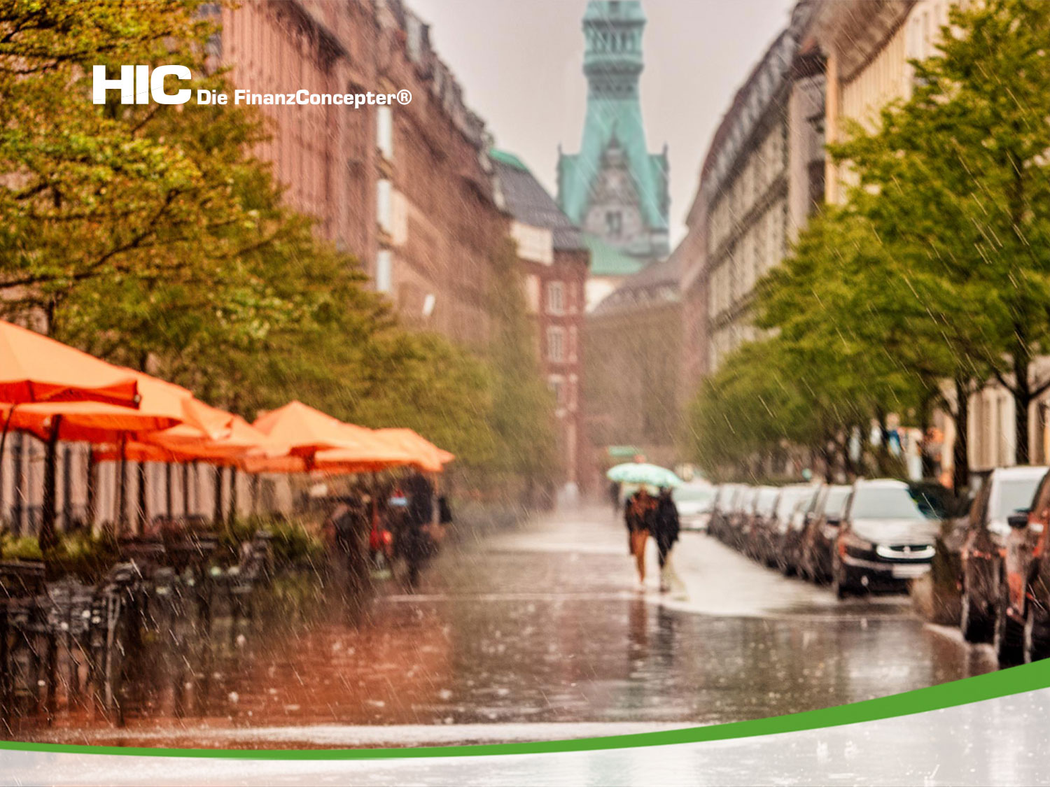  Eine überschwemmte Straße im Regen. Ein Paar mit Regenschirm überquert die Straße. Im Hintergrund ist der Turm des Hamburger Rathauses zu sehen.
