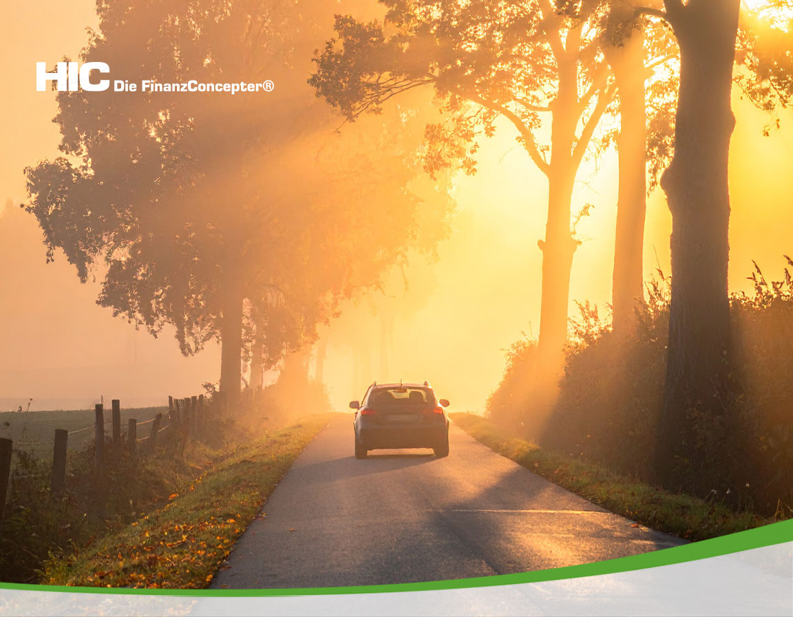 Ein Auto auf einer herbstlichen Straße im Gegenlicht bei tief stehender Sonne.