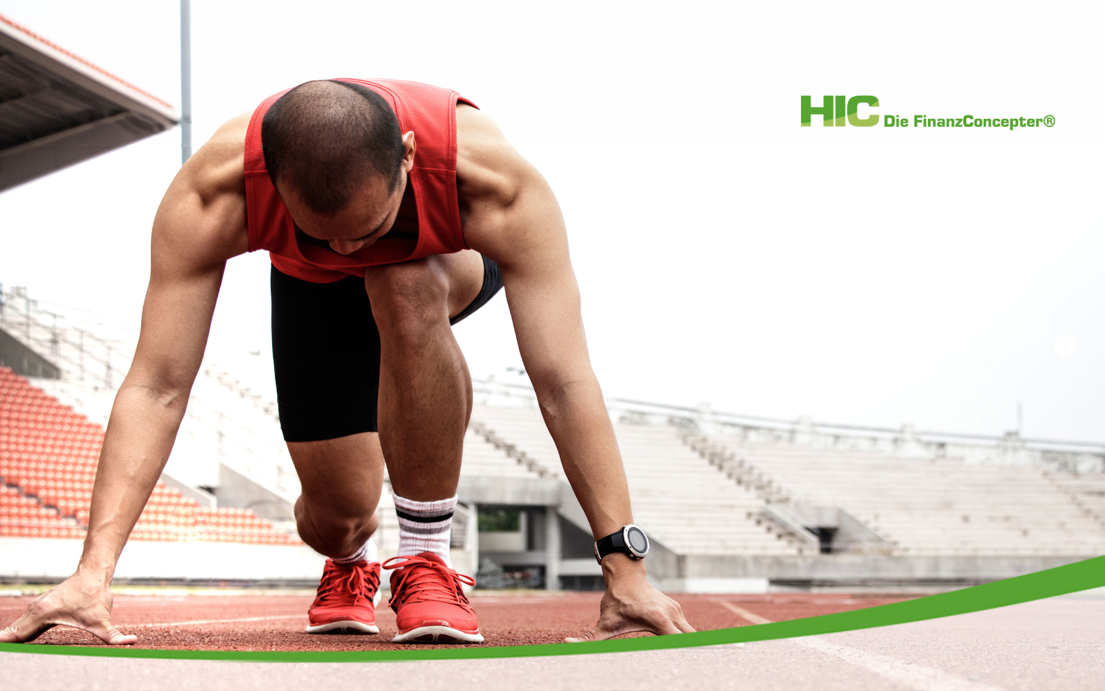 Muskulöser Mann im roten Sportoutfit in Startposition auf einer Laufbahn.